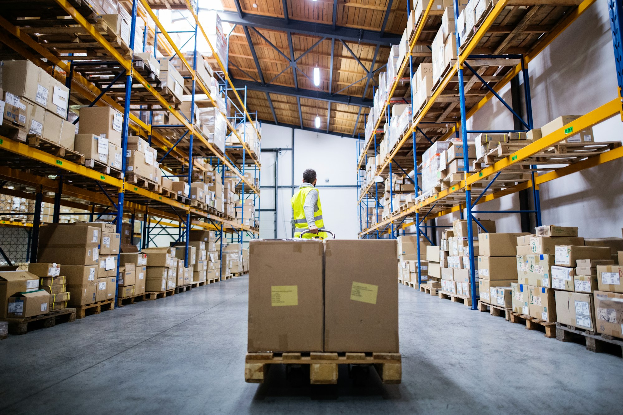 Male warehouse worker pulling a pallet truck.