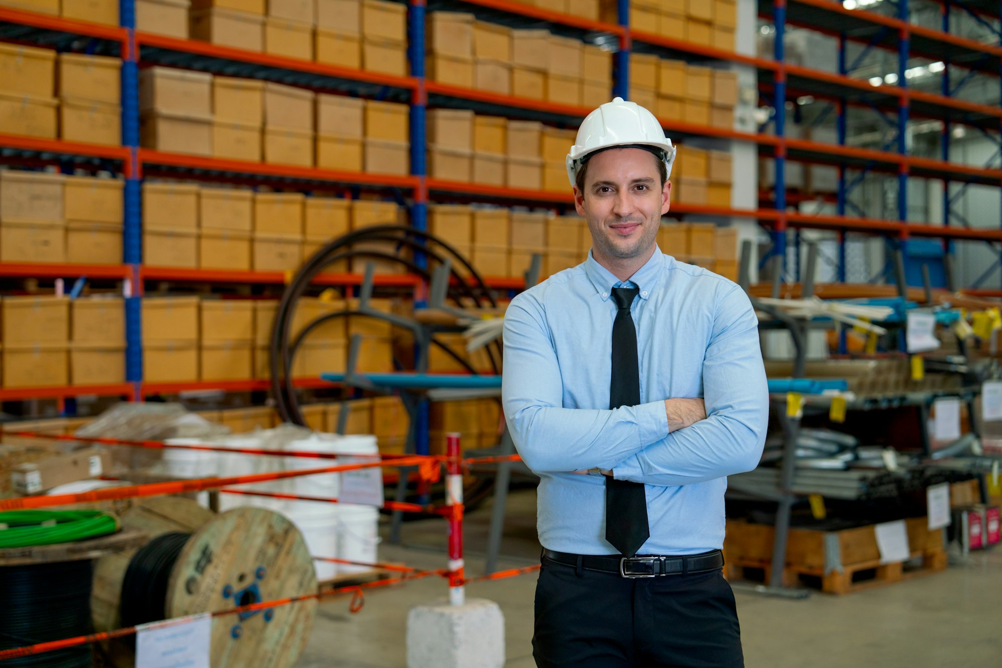 Professional business manager man stand in front of stack or shelves with parcel boxes in warehouse